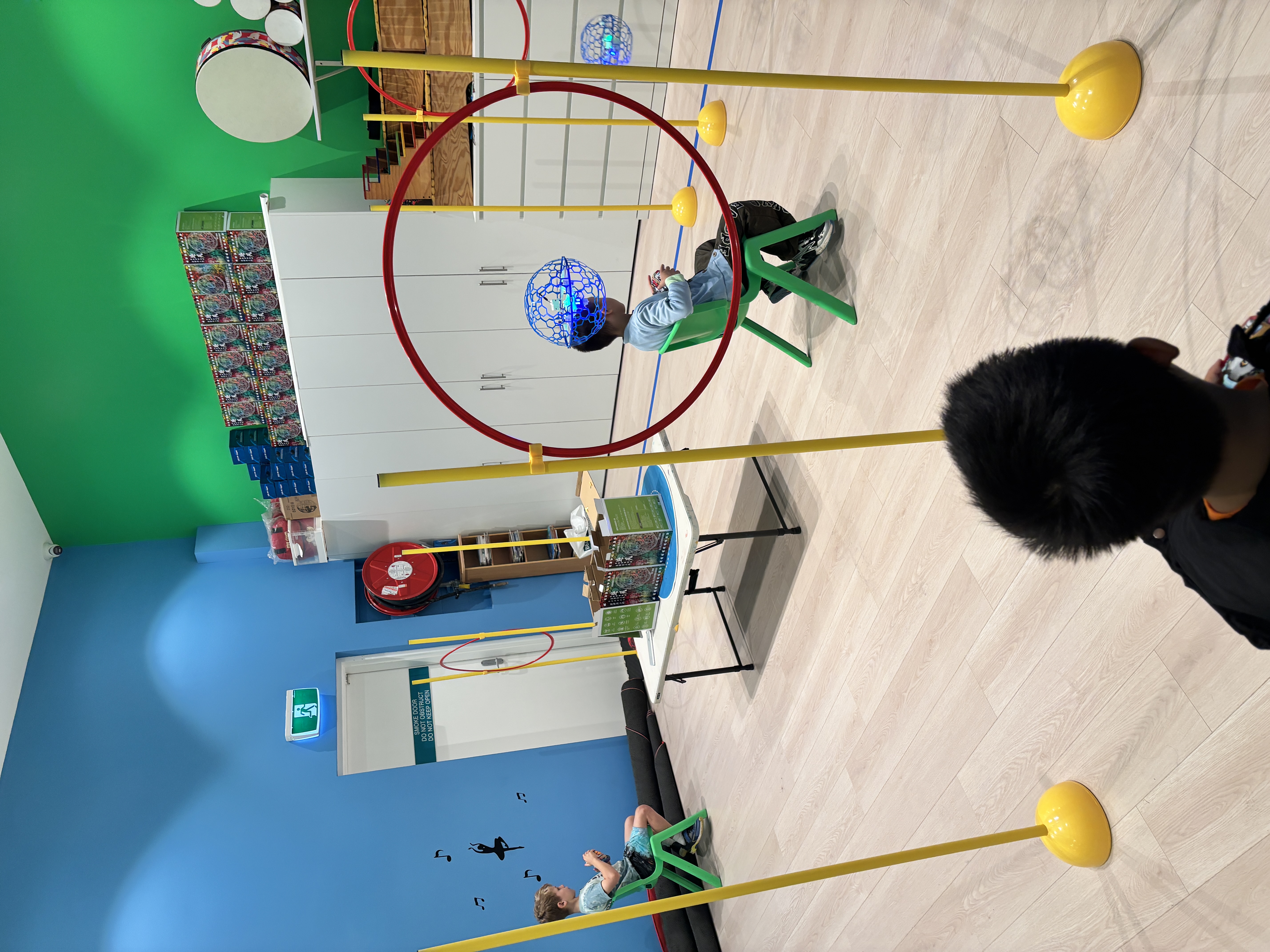 Children piloting illuminated caged drones through training hoops