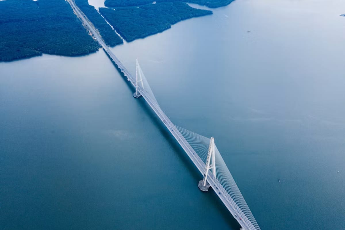 Aerial view of a long bridge crossing blue water